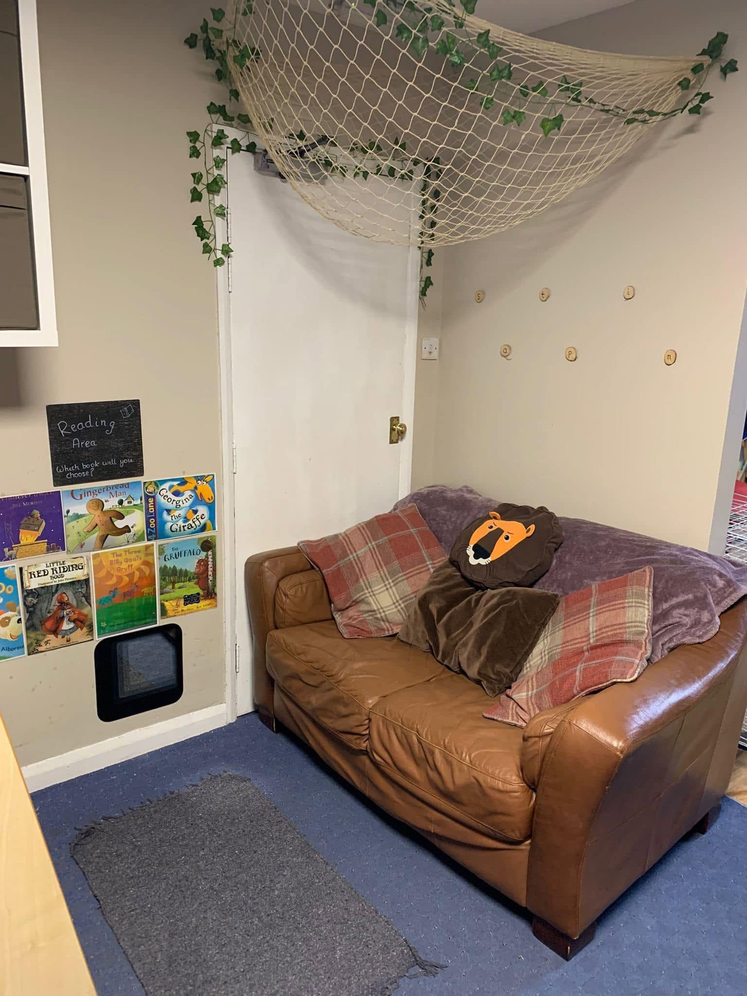 A quiet reading nook with a brown leather sofa beneath a canopy of ivy and netting.